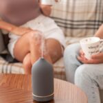 Aroma diffuser on table, people with coffee mugs.