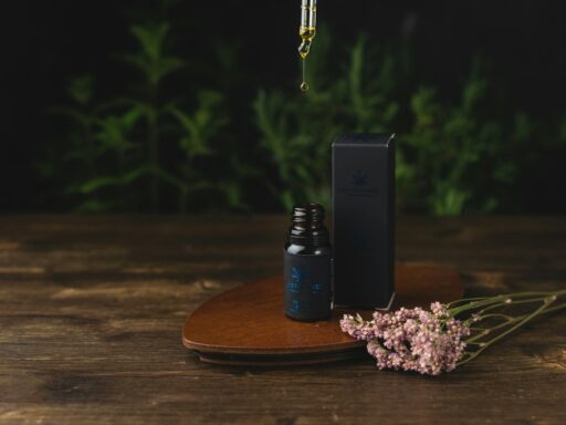 CBD oil bottle with dropper and flowers on table.