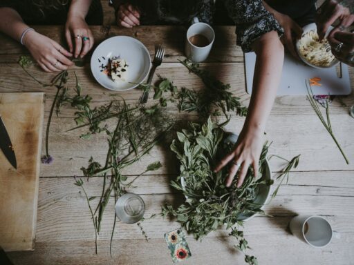 People preparing herbs and ingredients on wooden table.