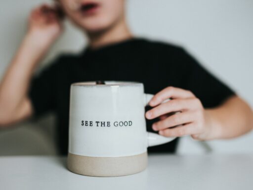 Child holding 'See the Good' mug.