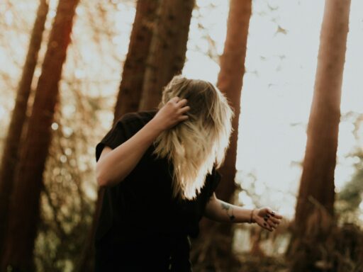 Person with blonde hair in a sunlit forest