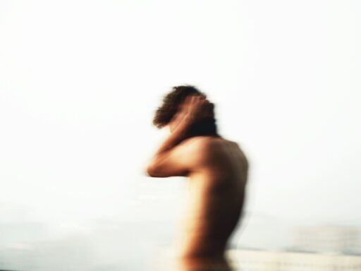 Blurry figure holding head with white background.